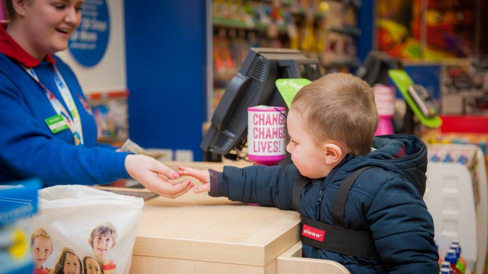 child using stool to pay