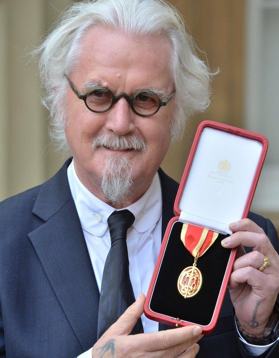 Billy Connolly poses after receiving his Kighthood