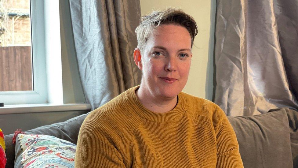 Vikki Heath sitting on a sofa in a mustard top