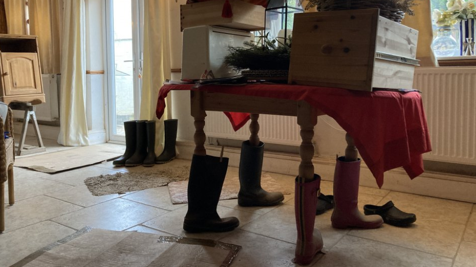 Table with wellies on the legs and objects piled on top