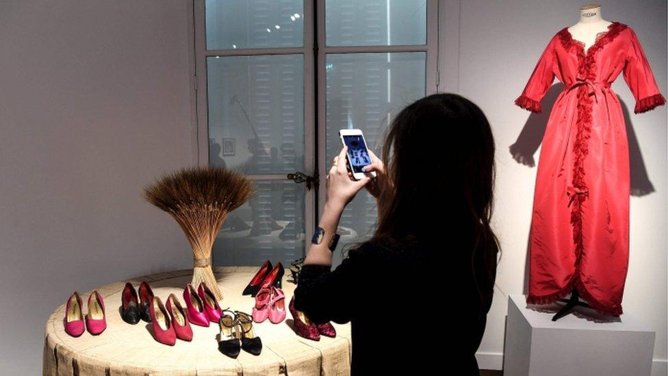 A visitor photographs some YSL shoes