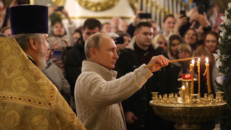 Image shows Putin lighting a candle