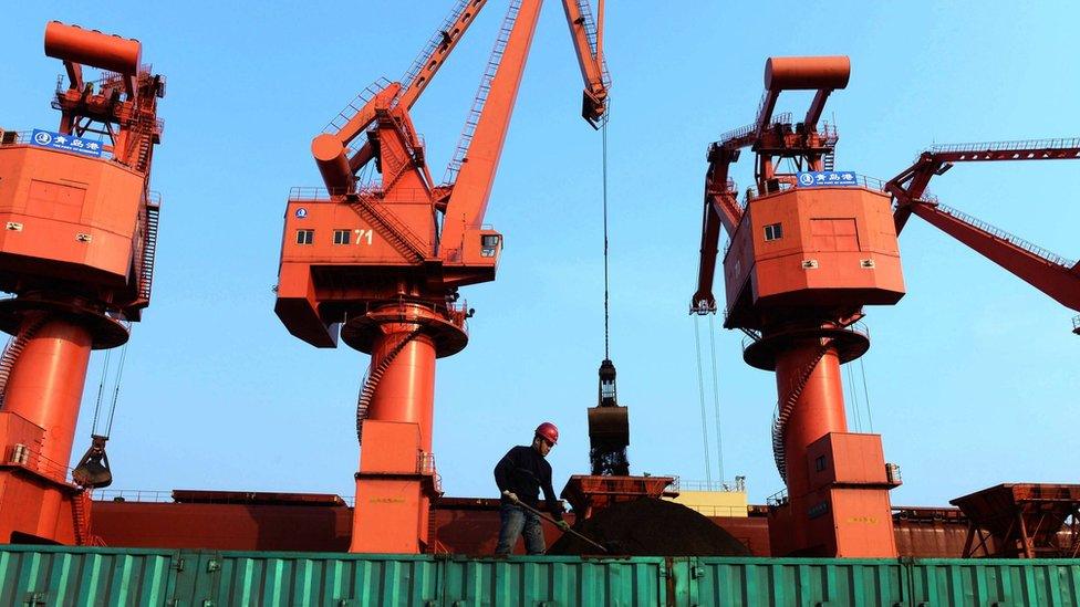 A worker shovelling iron ores on a truck in Qingdao port, eastern China