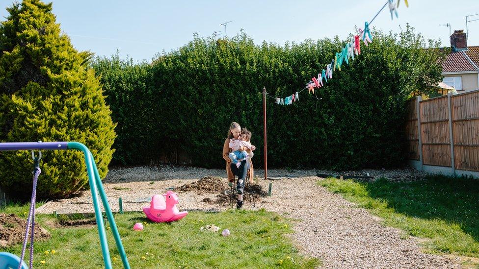 Toni and Amancia sitting in Toni's parents' garden, where her home was later built. Trees, a swing and a washing line can be seen.