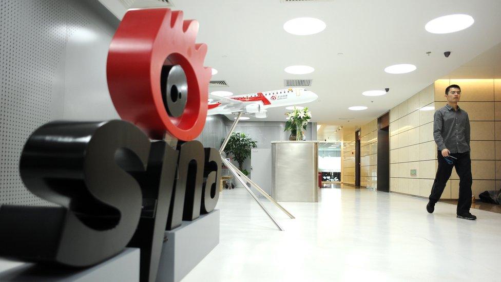 A man walks past the office entrance of Sina in Beijing