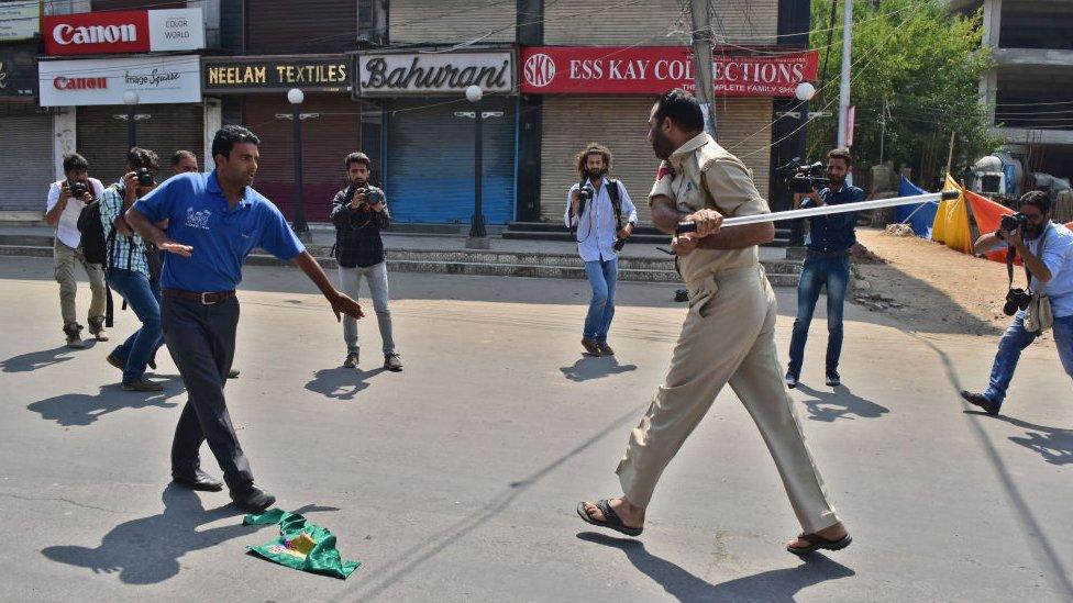 A police officer tries striking a Kashmir Shiite mourner during the procession. Authorities in parts of Srinagar imposed strict restrictions to prevent Shiite Muslims from taking part in Muharram procession.