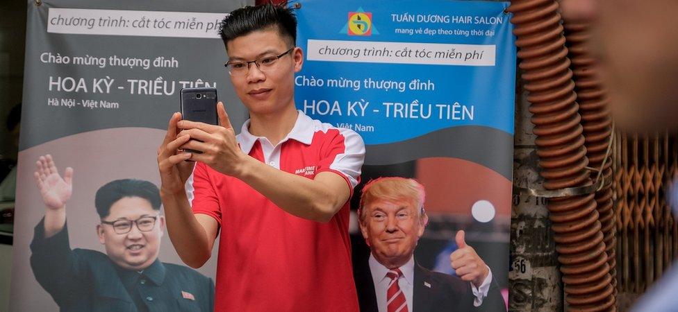 A man stands in front of a poster for the summit in Hanoi (20 Feb 2018)