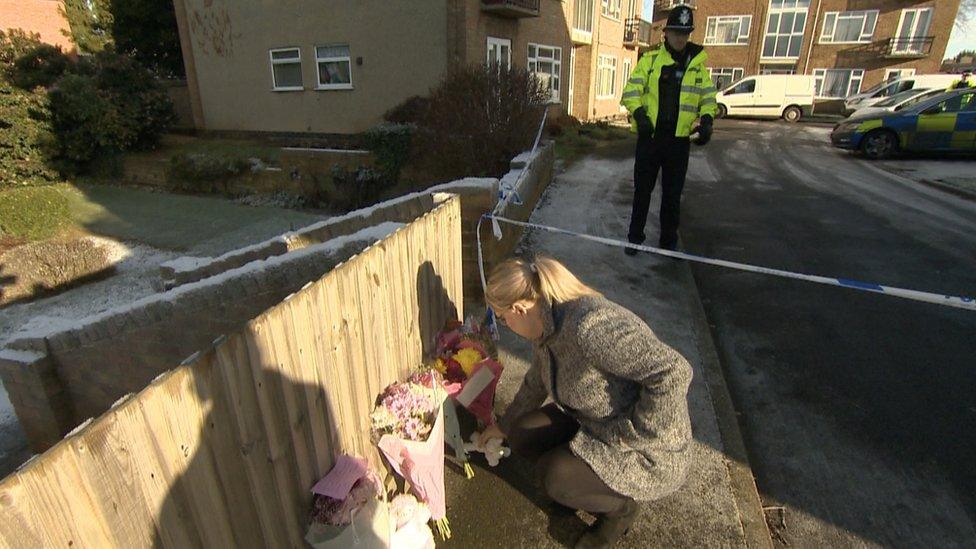 A woman lays flowers in Petherton Court in Kettering