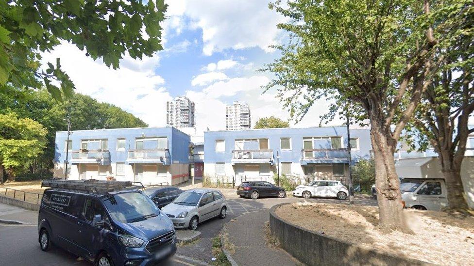 Image showing flats with painted blue walls on the Westbury Estate, with high rise towers in the background