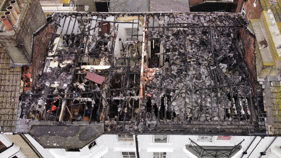 Close-up drone shot shows the extent of damage to the roof of the building