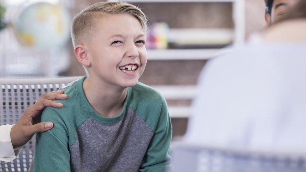 A boy laughing while looking at an adult