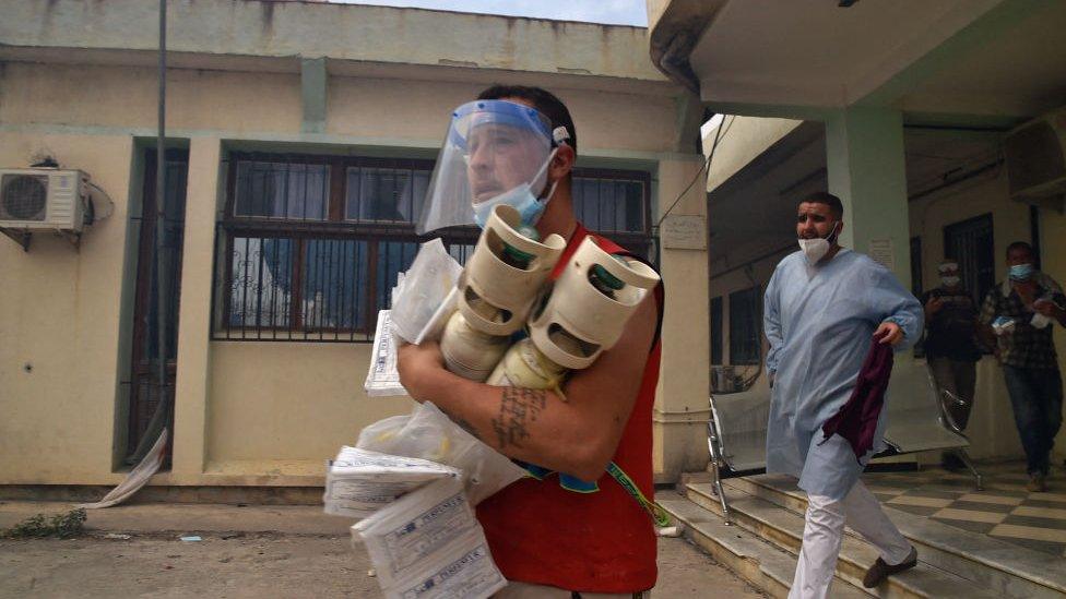 Medics evacuate a clinic during a wildfire in the forested hills of the Kabylie region