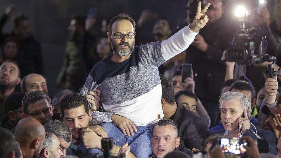 Lebanese actor Ziad Itani flashes a V for victory sign as relatives and friends carry him upon his return home in Beirut, 13 March 2018