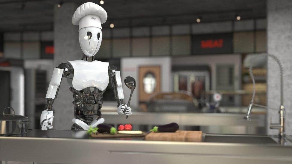 A humanoid robot chef cooks dishes in a restaurant kitchen