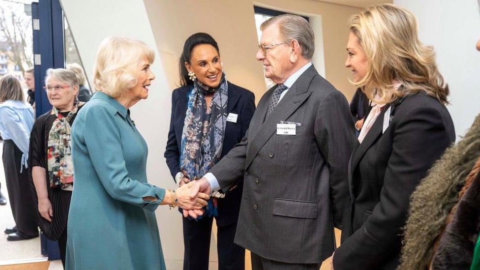 Queen Camilla shakes hands with Sir Gerald Ronson as others watch on