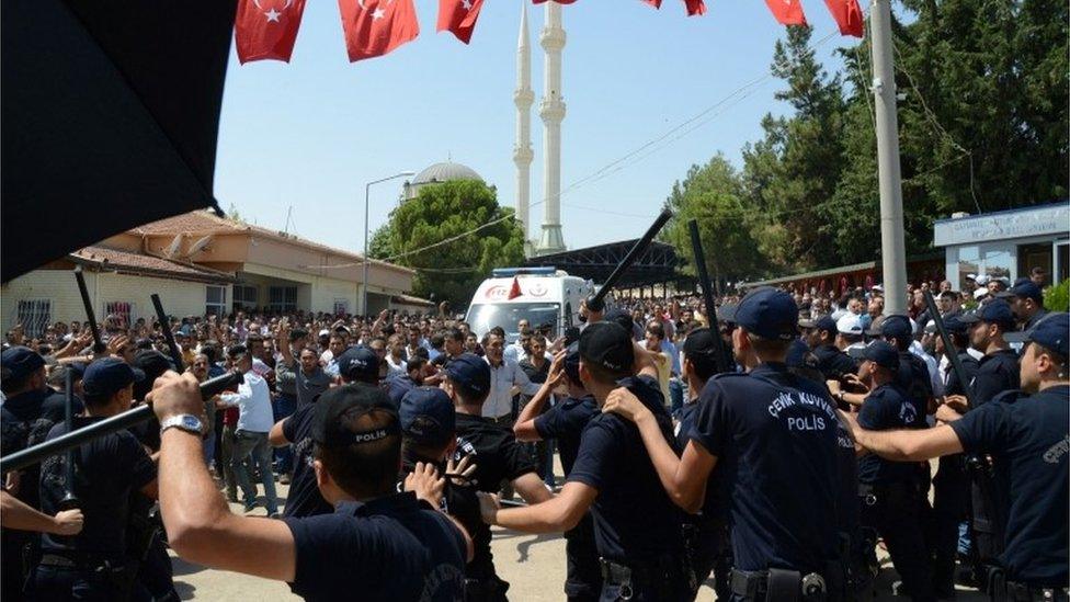 Turkish police hold their batons as people shout at government officers and police during the funeral of victims of the attack at a wedding party 21/08/2016