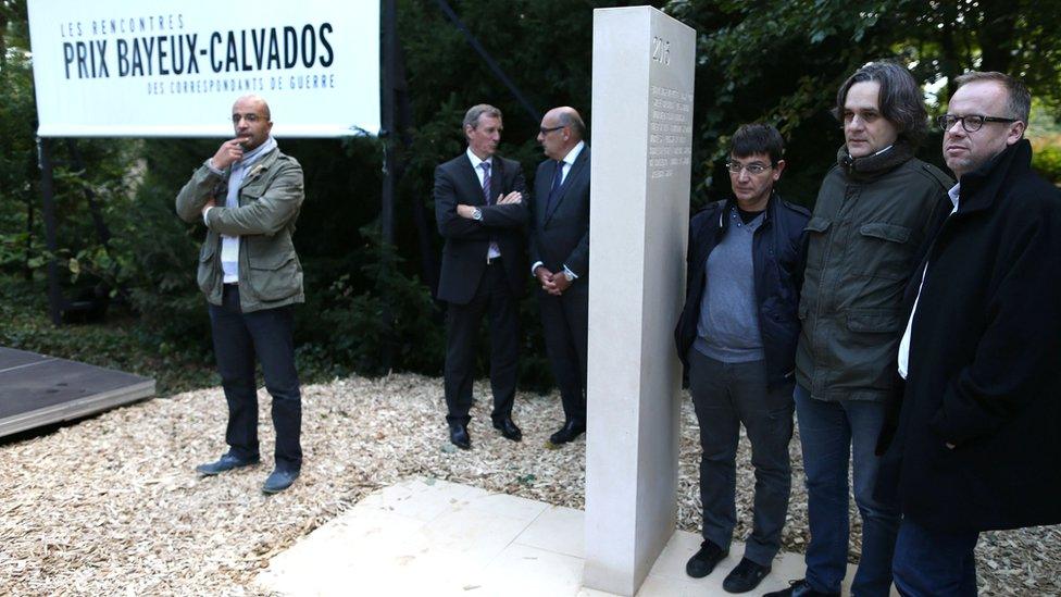 French cartoonist Riss (2nd R) stands alongside the general secretary of NGO Reporters Sans Frontieres (RSF) Christophe Deloire (1st R) and financial director of the satirical magazine Charlie Hebdo, Eric Portheault (3rd R), during the unveiling of a stone in honour of the war reporters killed in 2015 in the war reporters' memorial, on 8 October 2015 in Bayeux, north-western France, during the annual Bayeux-Calvados war journalism award week