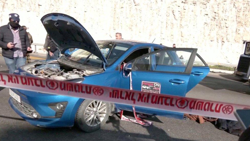 Israeli security forces inspect a car damaged during an attack by Palestinian gunmen at a checkpoint near the Israeli settlement of Maale Adumim, in the occupied West Bank (22 February 2024)