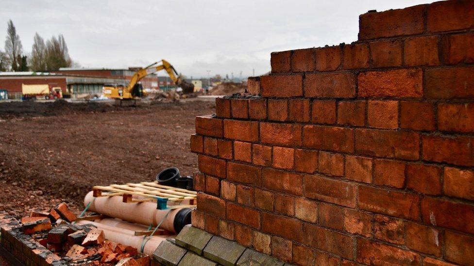 What is left of the wall and the building site behind it