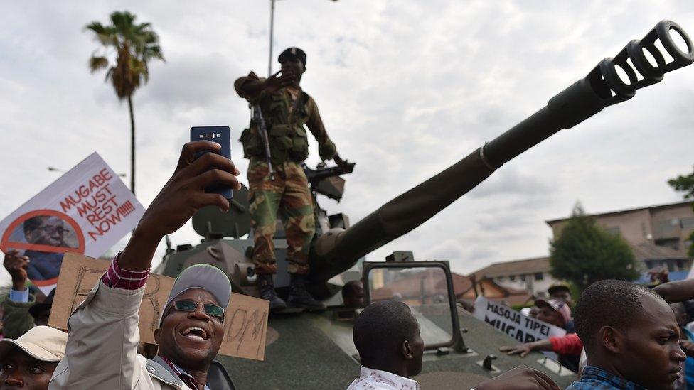 A man takes a selfie-picture of a Zimbabwean Defence Force soldier standing on a tank during a march in the streets of Harare, on November 18, 2017 to demand to the 93 year-old Zimbabwe's president to step down