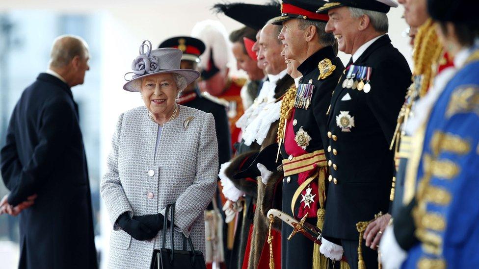 Queen Elizabeth II smiles as she waits with dignitaries