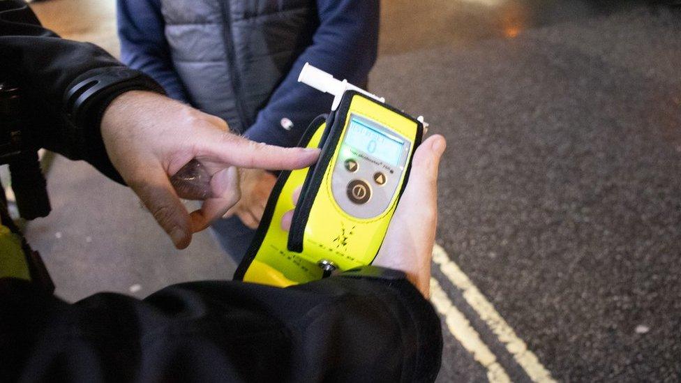 A police officer holding a breathalyser