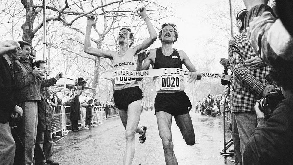 Black and white old image of two people finishing in the London marathon.