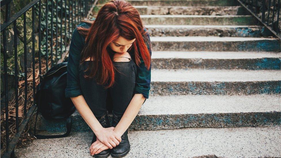 Sad teenager sitting with head down