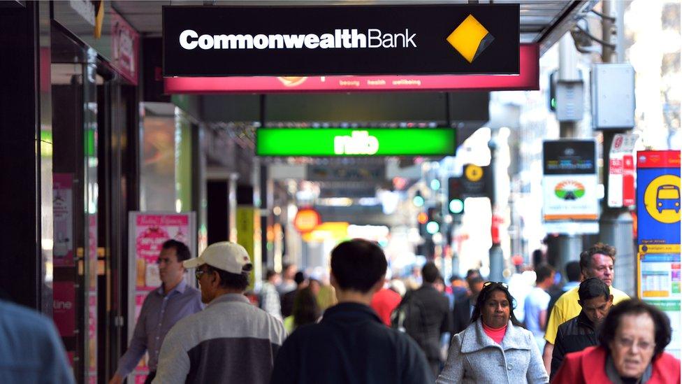 People on the street under Commonwealth Bank sign.