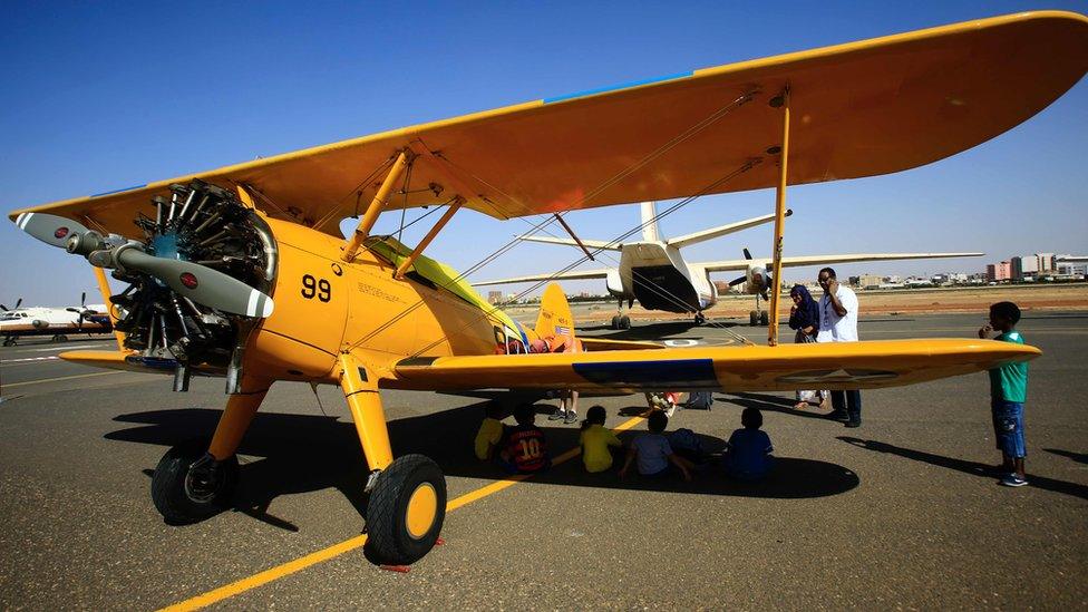 Children sit under the wing of a bright yellow vintage biplane in Khartoum, Sudan - Sunday 20 November 2016