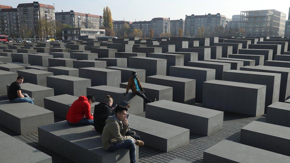 Visitors sit while visiting the Holocaust memorial in Berlin