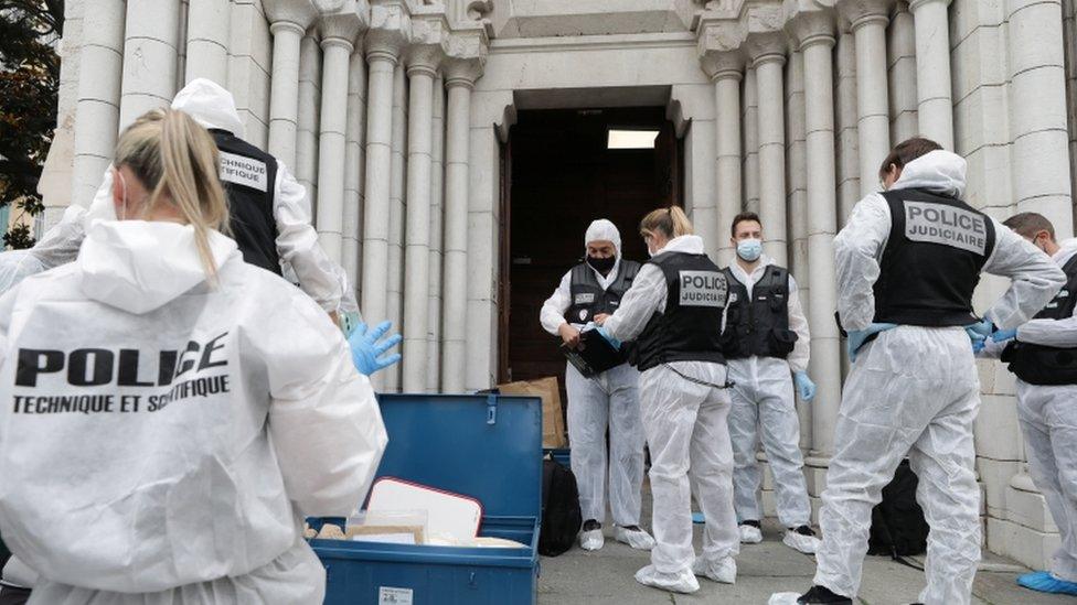 Forensic specialists stand at the entrance to the Notre Dame church in Nice