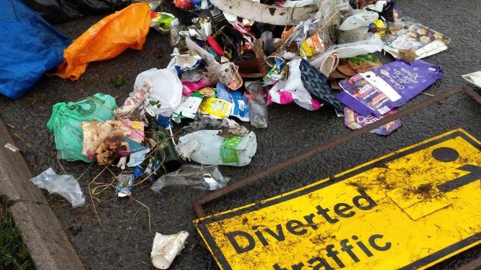 A diverted traffic sign with litter around it