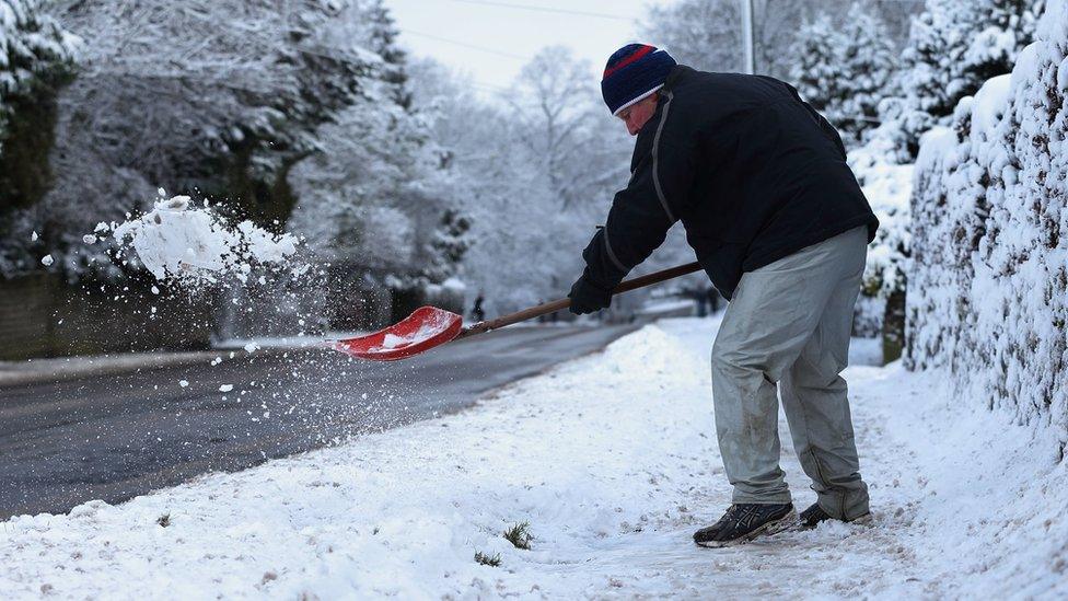 A man shovels snow in Buxton, Derbyshire