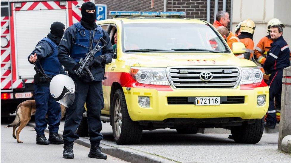 Several police officers hold guns in Molenbeek