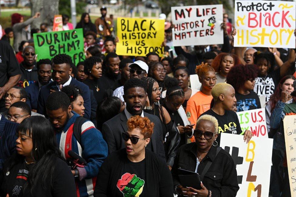 Demonstrators protest against Governor DeSantis' plan to eliminate a high school course in African-American history