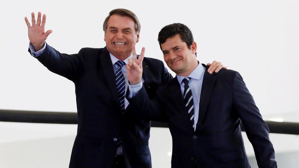 President Jair Bolsonaro and Justice Minister Sergio Moro gesture during a ceremony at the presidential palace in Brasilia