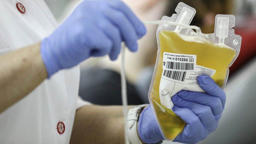 A lab worker holding a bag of plasma