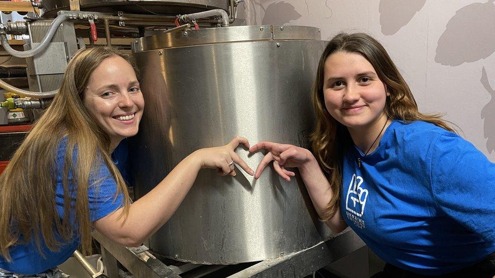 Two woman in front of a beer vat