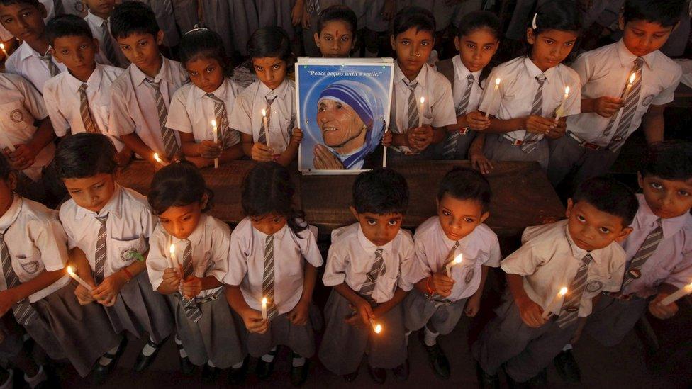 School children take part in a candlelight prayer ceremony as they hold a portrait of Mother Teresa on the occasion of her 101st birth anniversary celebrations in Kolkata, India