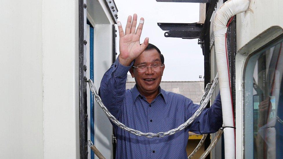 Cambodia's Prime Minister Hun Sen greets journalists out of shot, waving from the gap between two train carriages on 30 April 2016