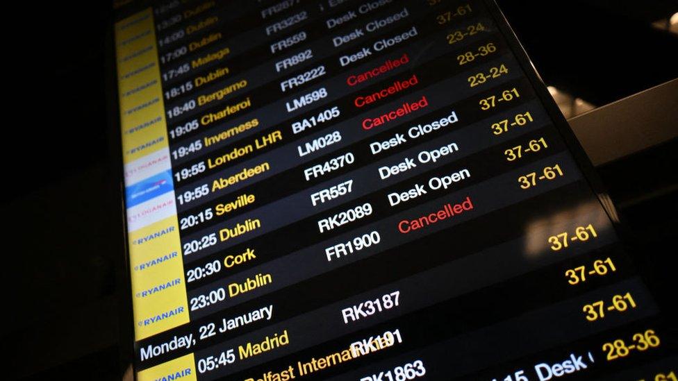 The arrivals board at Manchester Airport shows many flights cancelled or delayed due to high winds caused by Storm Isha.