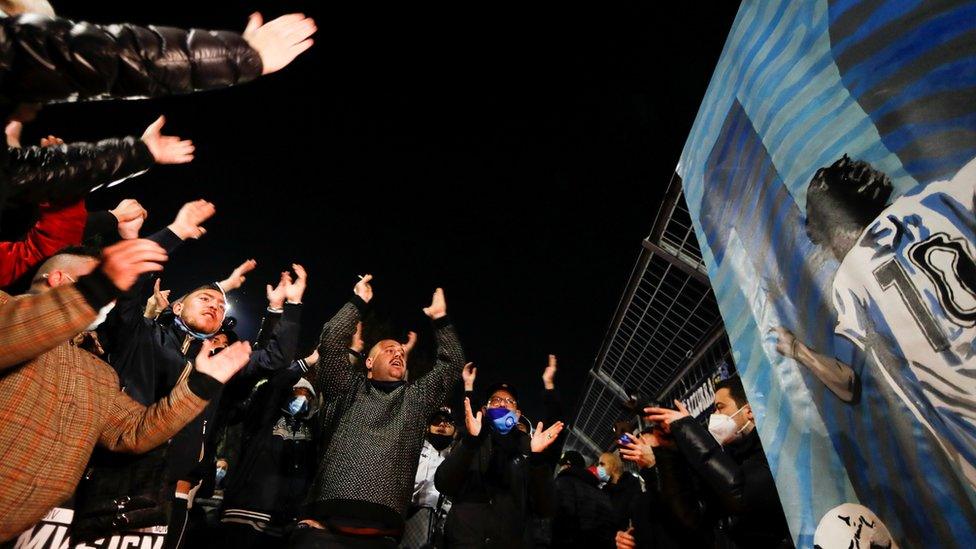 People hug each other after the death of the Argentine soccer legend Diego Maradona outside San Paolo stadium in Naples, Italy