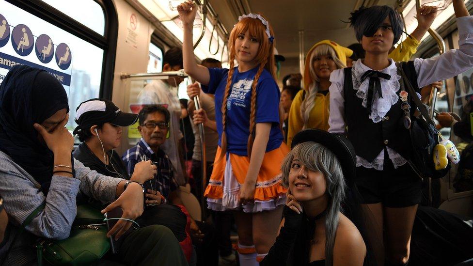 Malaysian cosplayers dressed in costumes pose amidst passengers onboard a Light Rapid Transit (LRT) train during a 'Commuter Cosplay' event in Kuala Lumpur on July 8, 2017.