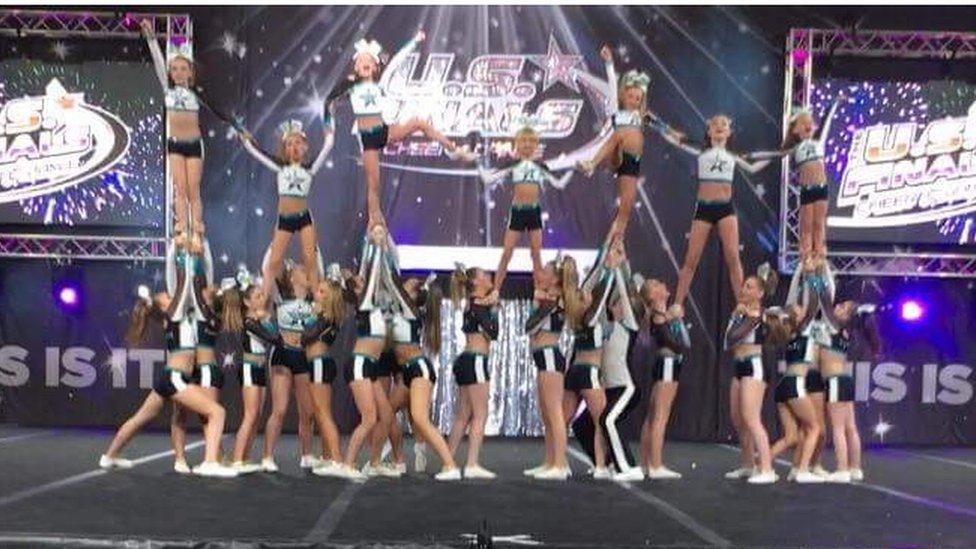 A group of young cheerleaders performing a pyramid stunt - with girls aloft in the air