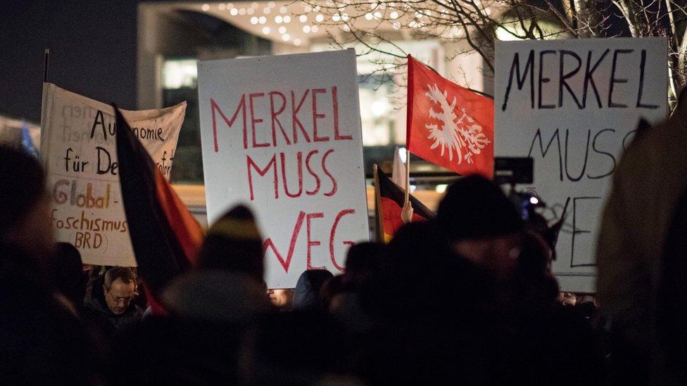 Participants of a vigil of right-wing groups are holding a sign that reads "Merkel must go" in front of the German Chancellery in Berlin, Germany, 21 December 2016.