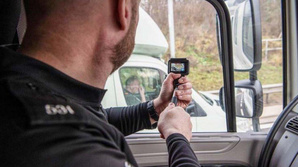 Police officer travelling in an HGV cab films a lorry in the next lane