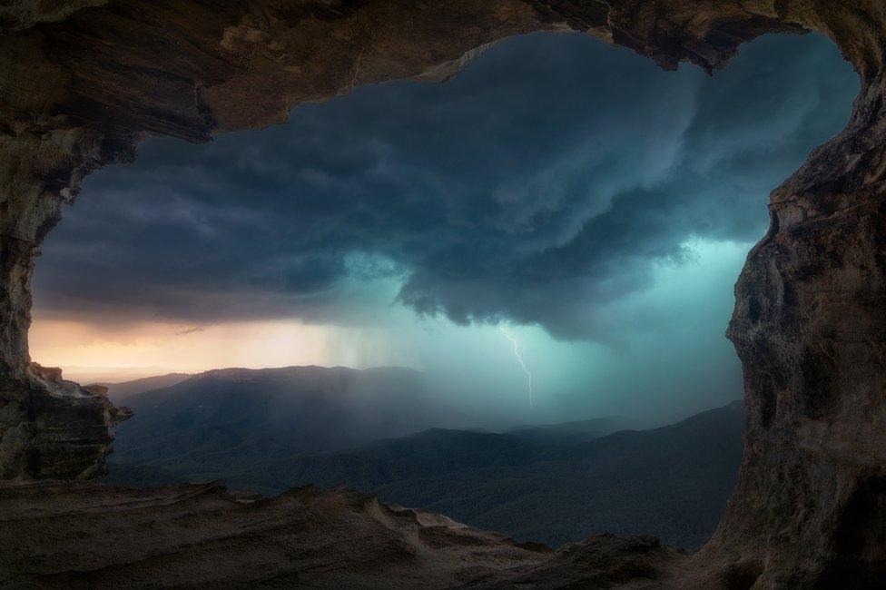 A mountainous landscape with lightning in the background