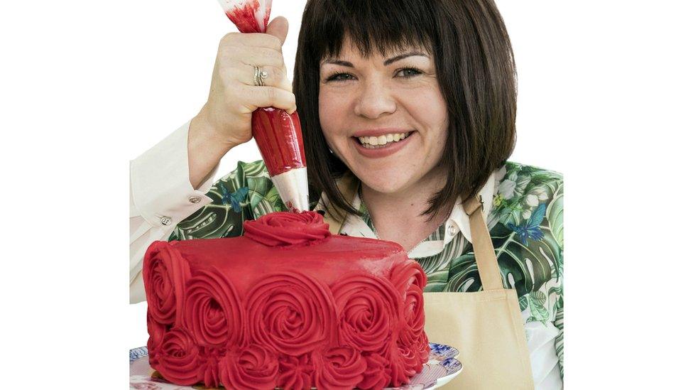 Briony smiles while icing a bright red cake