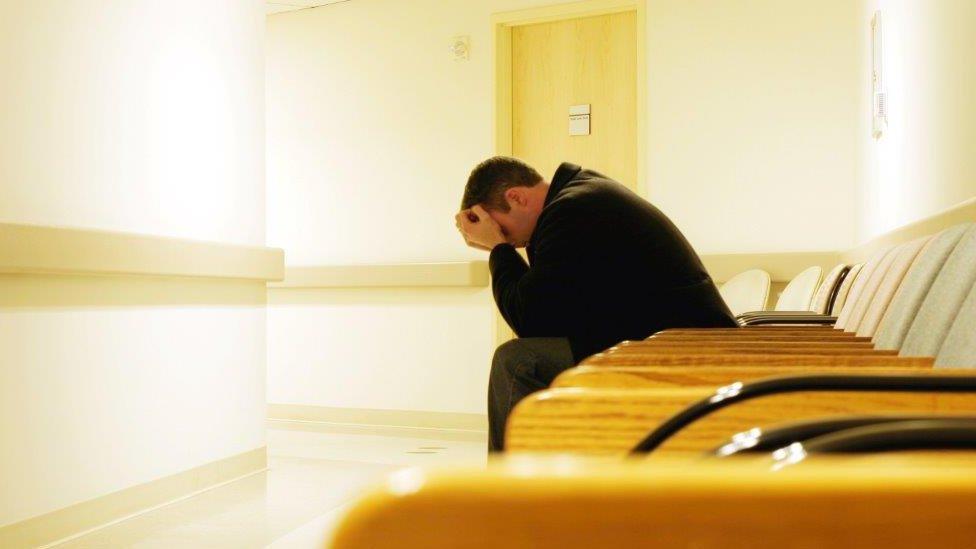 Patient in waiting room with head in hands